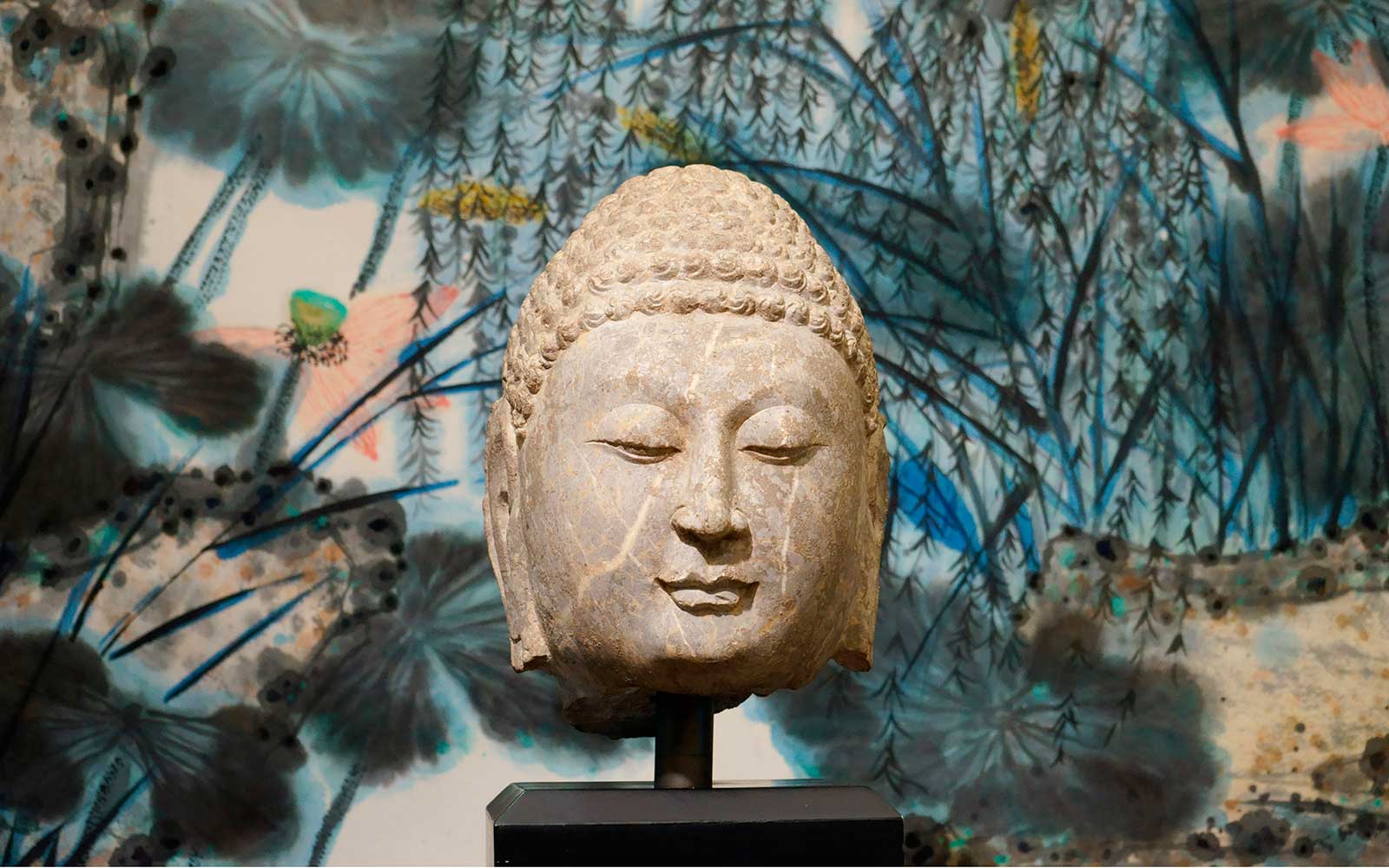 北齊 山東青州佛首　（背景：譚崇憲  「荷塘」紙本設色） Head of Buddha in Limestone, Northern Qi Dynasty (549-577 CE), h38cm.  (Background: <i>Lotus Pond</i> by Tan Chung Hsiang, 2008, ink and color on paper, 360x90cm)